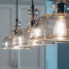 Een stijlvolle hanglamp boven een eettafel in een moderne keuken, die sfeer en karakter toevoegt.