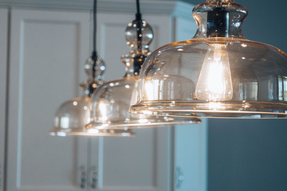 Een stijlvolle hanglamp boven een eettafel in een moderne keuken, die sfeer en karakter toevoegt.